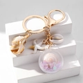 Detail van creatieve oceaan-sleutelhanger met schelp, zeester en hangers van paillettenbol - Paars