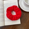 Close-up of red teddy fleece scrunchie on a book showing soft wool texture - Red
