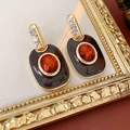 Detailed view of vintage enamel earrings with orange gems and small rhinestones on a gold frame - Brown Stud Earrings (Silver Pin)