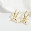 Primer plano de pendientes dorados cruzados sobre elegante fondo de seda blanca - Estilo X