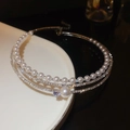 Nahaufnahme des Chokers mit weißen Perlen und funkelnden Diamanten auf silbernen Ketten - Mehrlagiger Perlen-Strass-Stil / Silber