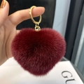 Close-up of deep wine red fluffy heart keychain with golden metal ring and chain detail - Burgundy