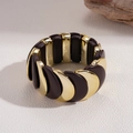Dettaglio di un ampio bracciale in acrilico con inserti dorati e finiture marrone scuro - Bracciale - Caffè Scuro