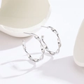 Minimalist silver Mobius twist C-shaped hoop earrings on white geometric stone - Steel Color Mobius Loop