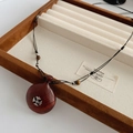 Primo piano della collana con ciondolo a croce in legno in scatola di velluto - Collana Marrone Rossastro / Marrone Rosso
