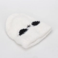 Close-up of white plush knit beanie featuring cute black patches and soft texture - One Size / White