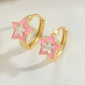 Macro shot of gold star hoop earrings with pink enamel and a sparkling white zircon center - Pink
