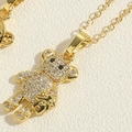 Close-up of golden teddy bear pendant with sparkling zircons and delicate link chain - Two Bears