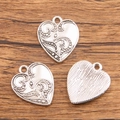 Three silver heart pendants with embossed floral patterns on natural wood background - 28C3-6 Embossed Dotted Heart