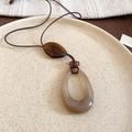 Détail du pendentif vintage en résine sur cordon ciré dans un plateau en céramique - Collier-Café-Ovale