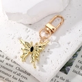 Detail of a gold butterfly keychain with black crystal inlay on white stone and newspaper - Black Rhinestone Gold Butterfly