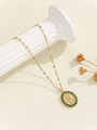 Close-up of gold Virgin Mary necklace with green cubic zirconia on a white pedestal - Gold Green Zirconia (TP-04193-03)