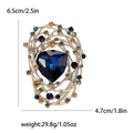 Vintage nest brooch with deep blue triangle crystal and gold metal swirls on white background - Blue