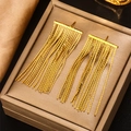 Elegante goldene S-förmige Kettentassel-Ohrringe auf einer edlen dunklen Schmuckschatulle - 18K Gold / Gold