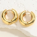 Dettaglio macro di orecchini a cerchio dorati spessi su pietra bianca ruvida - Fibbia per orecchio in oro 14K
