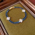 Detailed close-up of a gold bracelet with blue crystals on dark green velvet - Gold-Blue