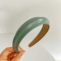 Close-up of glossy green leather sponge headband with brown lining and smooth texture - Green