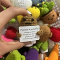Macro shot of handmade crochet potato holding a German positive potato encouragement card - Mini Potato German
