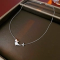 Dettaglio di una collana con ciondolo a balena argentata e zirconi su un vassoio espositivo - Argento