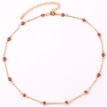 Close-up of gold-plated evil eye necklace with red and black beads on white backdrop - Red Necklace