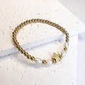 Detailed close-up of golden beads, baroque pearls and star charm on a stone surface - Pentagram / Gold