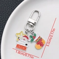 Detail of Christmas keychain with Santa and snowflake charms on a white ceramic plate - ER845-White K Enamel Santa Chimney Sock U-shaped Keychain
