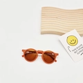 Detail shot of orange round frame kids sunglasses with dark lenses on a clean backdrop - Orange