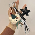 Beige plush bear keychain with green party hat, black star charm, and silver heart carabiner - Charm / White Puppy