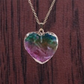 Nahaufnahme des Regenbogen-Kristallherz-Anhängers mit Goldkette auf dunklem Holz - Edelstahl/Legierung / 45+5cm / Regenbogen Aura - Edelstahl