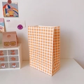 Orange checkered pattern paper gift bag for packaging on a white desk backdrop - Orange