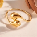 Macro shot of polished gold-tone teardrop bangle on a warm textured aesthetic background - Water Drop Style (40-C-4) / Gold