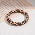 Nahaufnahme eines Vintage-Armreifs mit Leopardenmuster auf klassischem Zeitungsdekor - Armreif-Braun-Schmal