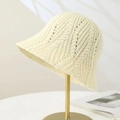 Chic cream white hollow knit bucket hat displayed on a gold metal stand with sun shadows - One Size Adjustable / Cream