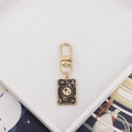 Close-up of gold alloy The Magician tarot card keychain with black enamel sun and moon - Magician