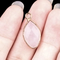 Marquise pink quartz pendant with gold plated edge held between fingers for size - Rose Quartz