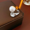 Detalle macro de un anillo abierto estilo francés con perla blanca y cristal tallado - Plata/Transparente
