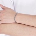 Primer plano de pulsera de cadena trenzada plateada en muñeca sobre fondo blanco - Plateado