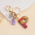 Detail of P-shaped resin keychain with purple tassel and colorful star sequins in a sphere - Letter P