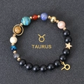 Detail of Taurus zodiac bracelet with black matte beads and celestial gold pendants - Taurus