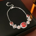 Primer plano detallado de una pulsera de flores de plata con un gran circón rojo ovalado - Pulsera / Plata/Rojo Anaranjado