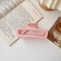 Gros plan d'une grande pince à cheveux rose mat posée sur un livre au décor chaleureux - Carré Grand Mat Rose Clair