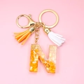 Detail of resin letter N keychain with gold foil flakes and orange white tassels - Letter N