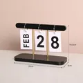 Minimalist black wood and gold metal flip calendar with white date cards on desktop - M-Style Black