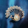 Golden peacock-shaped brooch with sparkling rhinestones and a large elegant pearl - Peacock Pearl Brooch