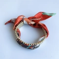 Dettaglio del bracciale a foulard rosso e arancione con catena di perle d'oro opaco - B27 Rosso Stretto