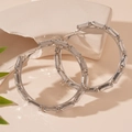 Macro detail van zilverkleurige oorringen met rechthoekige kristallen op steenbasis - Zilveren Strass (925 Zilveren Pin)