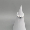 Detailed macro view of white bead stretch ring with blue evil eye charm on display stand - Adult Diameter 17-18mm / White-Gold
