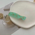 Dettaglio di un pettine per capelli verde con fiori su un piatto bianco decorativo - Verde