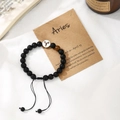 Adjustable black beaded Aries zodiac bracelet with symbol charm on descriptive card - Aries