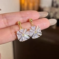 Gros plan de boucles d'oreilles flocon de neige dorées avec cristaux de zircone brillants - 925 Sterling Silver Earring Post - Flocon de Neige Rayonnant - Or